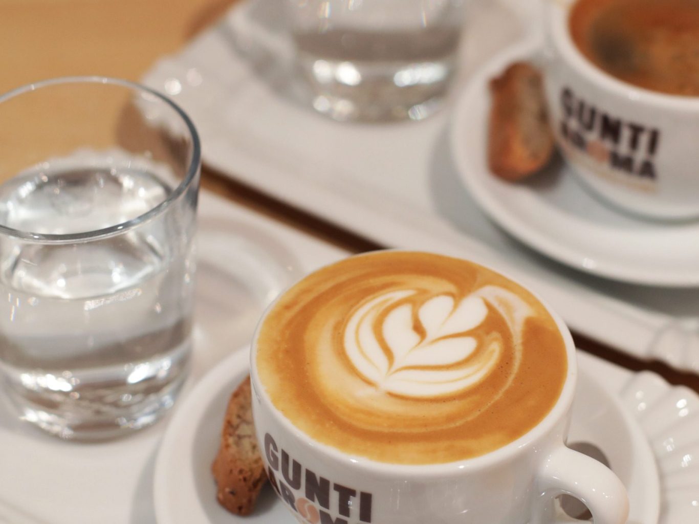 Kaffee angerichtet auf einem rechteckingen Teller mit einem Glas Wasser.