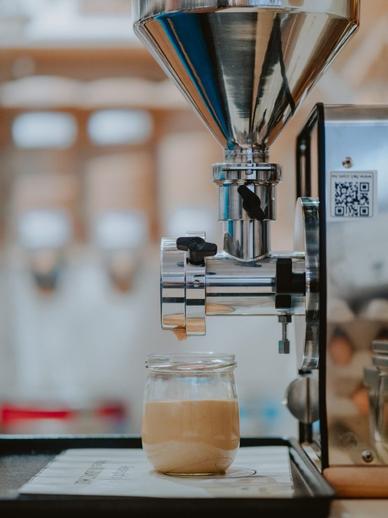 Nussmus-Mühle mit Vorratsglas, dass mit Nussmus frisch befüllt wurde.